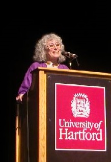 Marge Schneider speaking at a podium at the University of Hartford