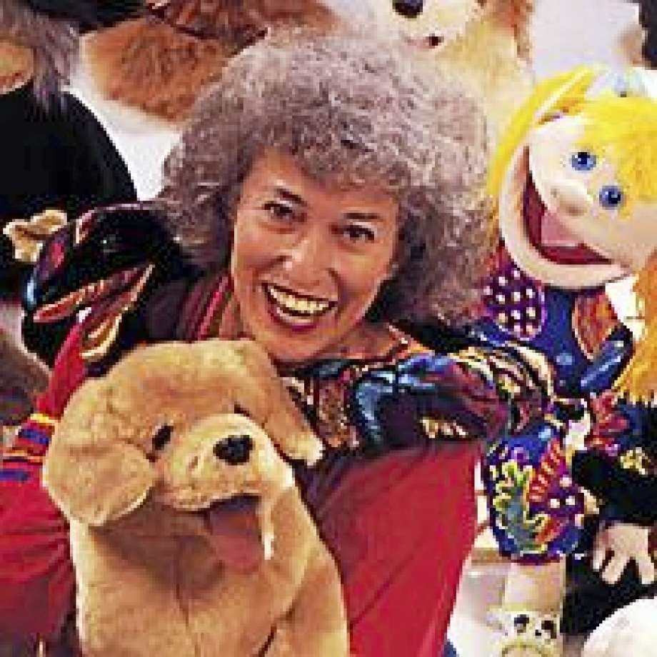 Marge Schneider seated with puppets around her